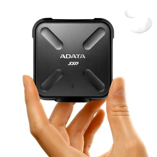 A hand gripping a small black box labeled "ADATA," showcasing the brand's logo prominently on the surface.